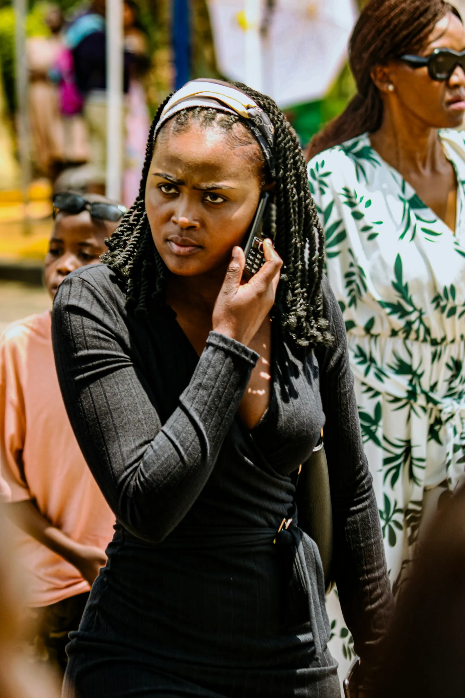A young woman talks on her phone outdoors on a busy street