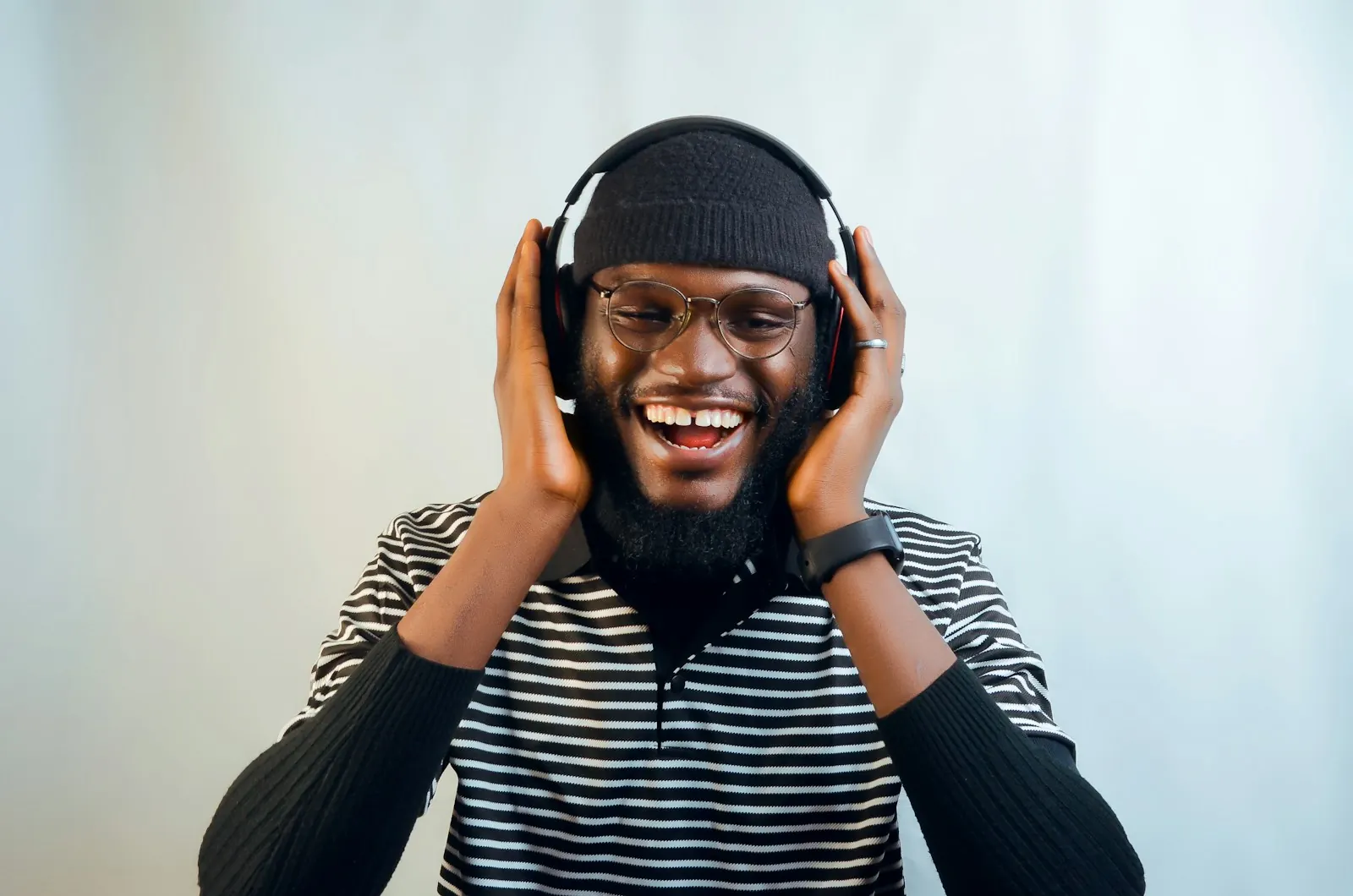 A smiling man with glasses listens through headphones