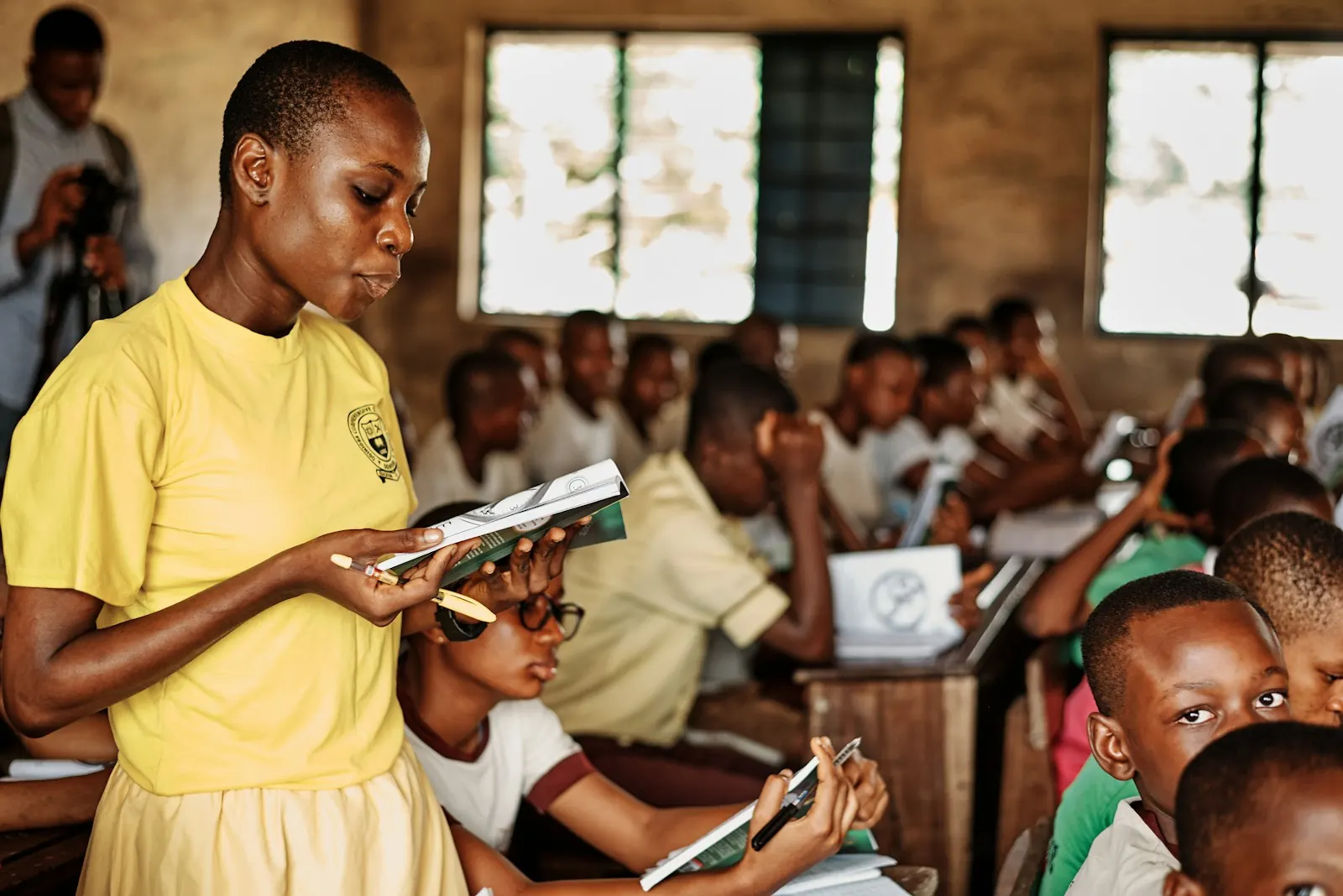 Secondary-school students in a classroom in Port Harcourt, Nigeria, one reading from a booklet